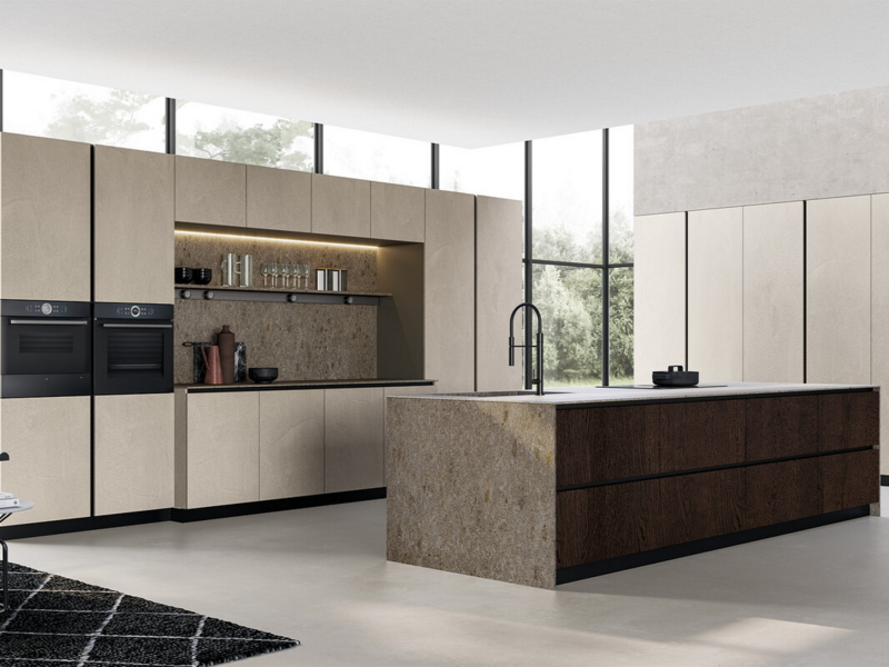 Base and tall units CX 11 in melamine perla with black curved groove. Island base units CX 11 in heat treated oak wood with black curved groove. Back panels, side panels and worktop in stoneware Gris Abujardado Geo.